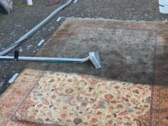 This is a photo of a floral rug that is being steam cleaned. The bottom half has been completed and the top half is being done works carried out by Buckhurst Hill Carpet Cleaning