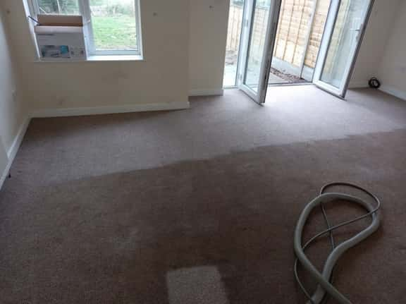 This is a photo of an empty living room with a brown carpet that is in the process of having its carpets steam cleaned works carried out by Buckhurst Hill Carpet Cleaning