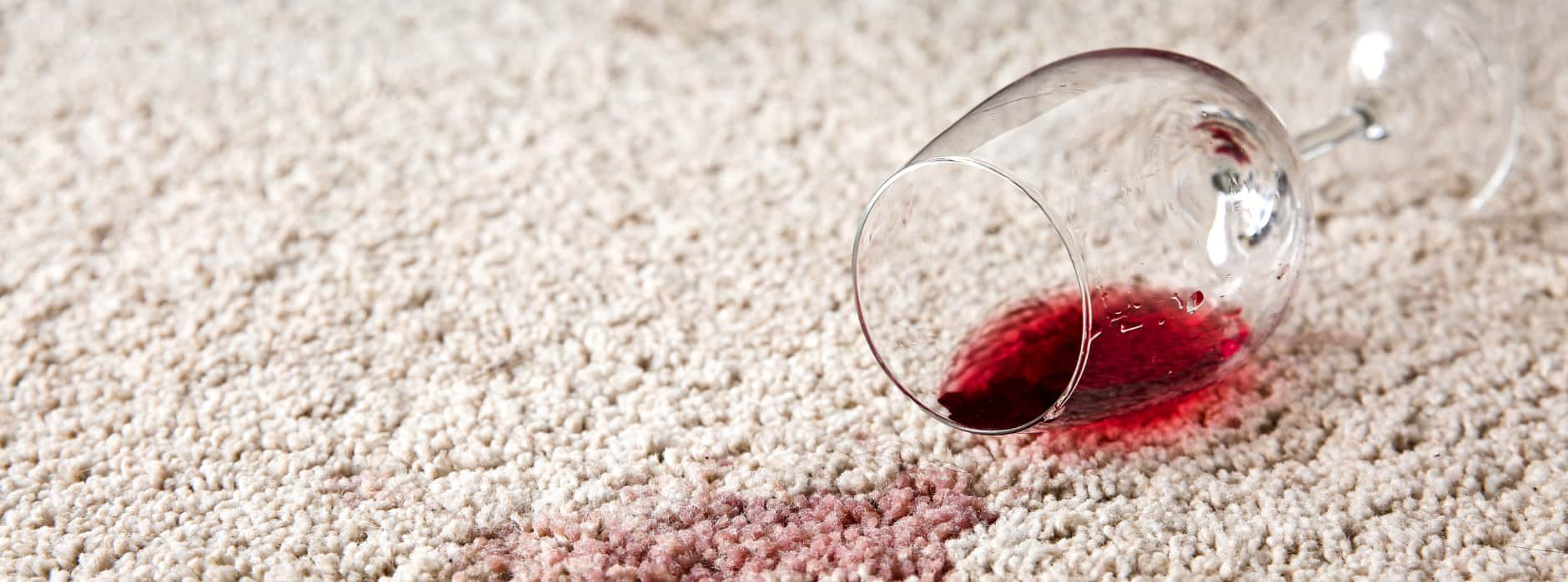 This is a photo of Buckhurst Hill Carpet Cleaning red wine which has been spilt on a cream carpet. The glass is on its side.